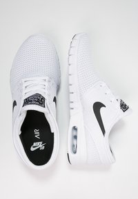 Bílé tenisky Nike Air se síťovaným svrškem, černým logem swoosh, polstrovanou podrážkou a viditelnou vzduchovou jednotkou. Obsahují texturované tkaničky a polstrovaný límec.