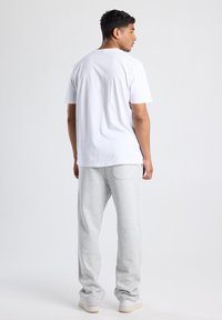 T-shirt en coton blanc à manches courtes, assortie à un pantalon de jogging gris clair en tissu doux, doté d'une poche arrière et d'une coupe décontractée.