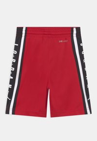 Röda idrottsshorts med Dri-FIT-tyg, svarta sidosträck med vit text, och elastisk midja.