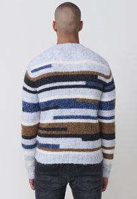 Gebreide trui met meerkleurige strepen in blauw, bruin, zwart en wit; ronde halslijn, lange mouwen en geribde onderkant; zachte textuur.