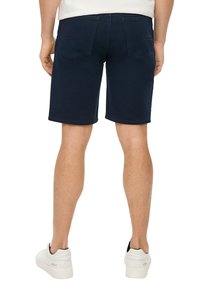 Granatowe szorty dżinsowe w prostym kroju, z dwoma tylnymi kieszeniami i subtelną fakturą splotu. Stylizowane z białymi sneakersami.