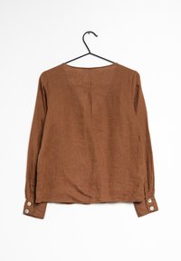 Chemise en lin marron à manches longues avec un col rond, dotée de poignets boutonnés et d'une coupe décontractée. Texture lisse et design simple.