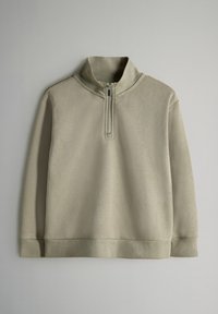 Vaaleanbeige pitkähihaine neule, jossa on vetoketjullinen mock-kaulus. Valmistettu pehmeästä materiaalista, jossa on resorit hihansuissa ja helmassa. Yksinkertainen ja minimalistinen muotoilu.