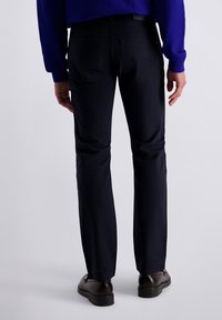 Zwarte broek van een gestructureerde stof, met een rechte pijpdesign, twee achterzakken en gecombineerd met donkere, gepolijste schoenen.