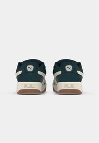 Dark teal suede sneakers with beige accents and gum rubber sole. Features logo on the heel and padded collar for comfort.