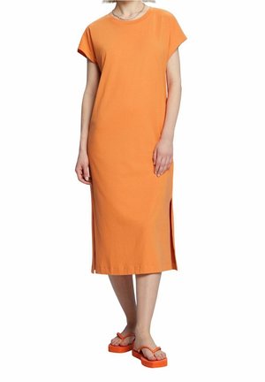Robe midi en coton orange avec manches courtes et fentes latérales, associée à des sandales compensées orange. Design simple et coupe droite.