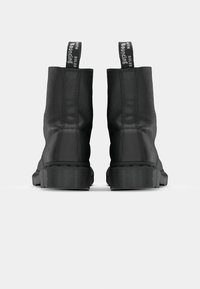 Black ankle boots made of textured leather, featuring rubber soles, a ribbed edge, and pull tabs with printed text on a white background.
