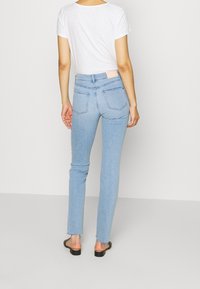 Vaaleansiniset farkut, joissa on slim fit -leikkaus, takataskut, korkea vyötärö ja hieman rääsyinen helma. Yhdistettynä yksinkertaiseen valkoiseen t-paitaan.