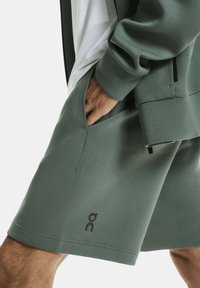 Groene katoen shorts met zijzakken, met een eenvoudig ontwerp en een logo op het linkerbeen. Zachte textuur, relaxte pasvorm.