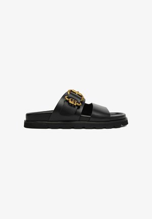 Black leather slide sandal with double straps, gold buckle detail on the upper strap, and a thick treaded sole.