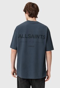 Tmavě modré bavlněné tričko s krátkým rukávem. Na zádech černý potisk s textem: "ALLSAINTS," japonské znaky a "LONDÝN" pod tím.