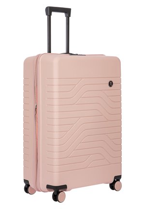 Valigia rigida di colore rosa con un design a onde testurizzato, manico estraibile e quattro ruote. Dotata di chiusura a zip e lucchetto di sicurezza.