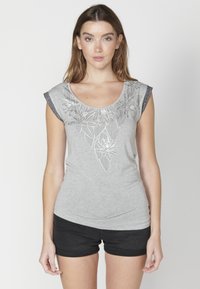 Šedé tričko s krátkymi, tmavými, textúrovanými rukávmi a kvetinovým vzorom. Mäkká tkanina; priliehavý strih s zakriveným výstrihom a zberaným detailom na boku.