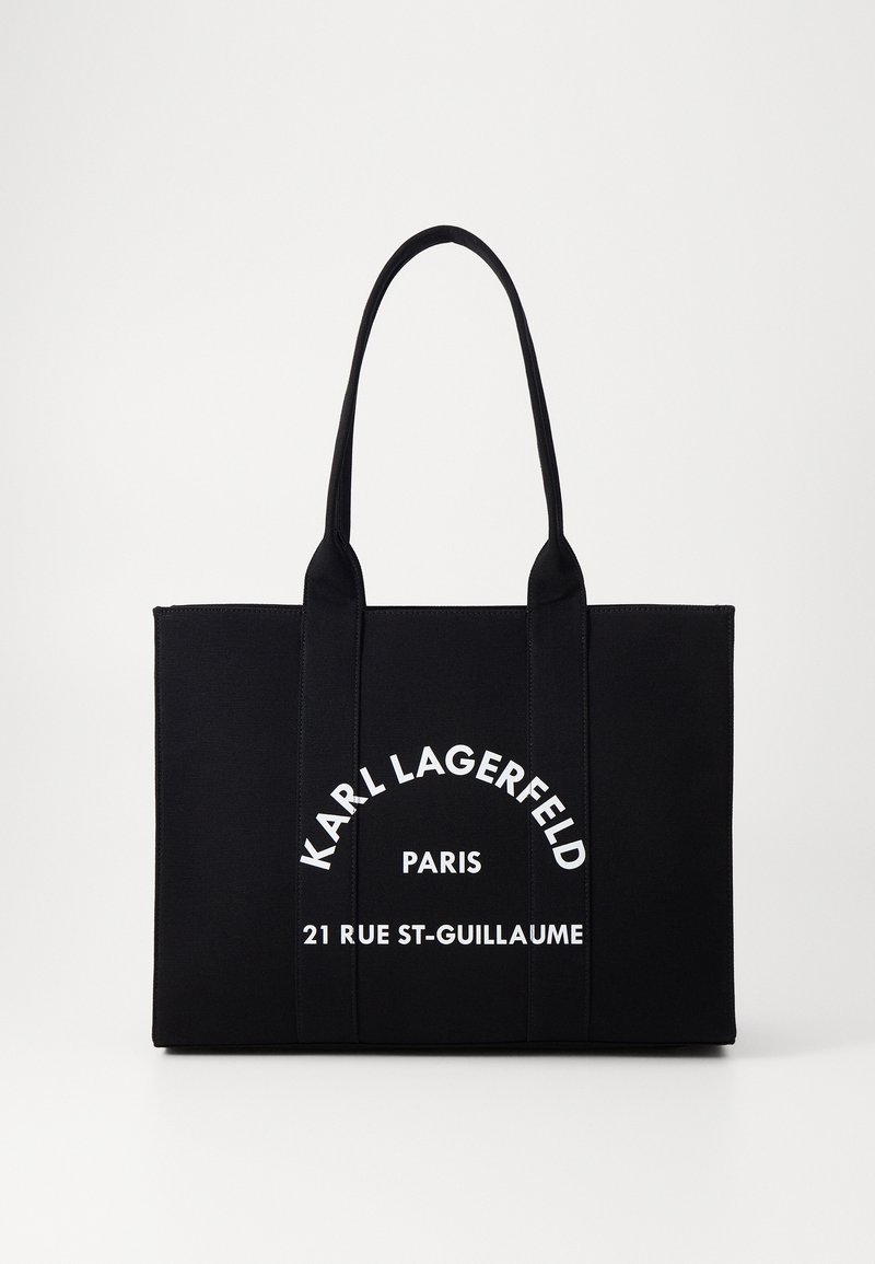 Borsa tote nera in tessuto, con due manici robusti e testo bianco: "KARL LAGERFELD PARIS 21 RUE ST-GUILLAUME" in un design curvo.