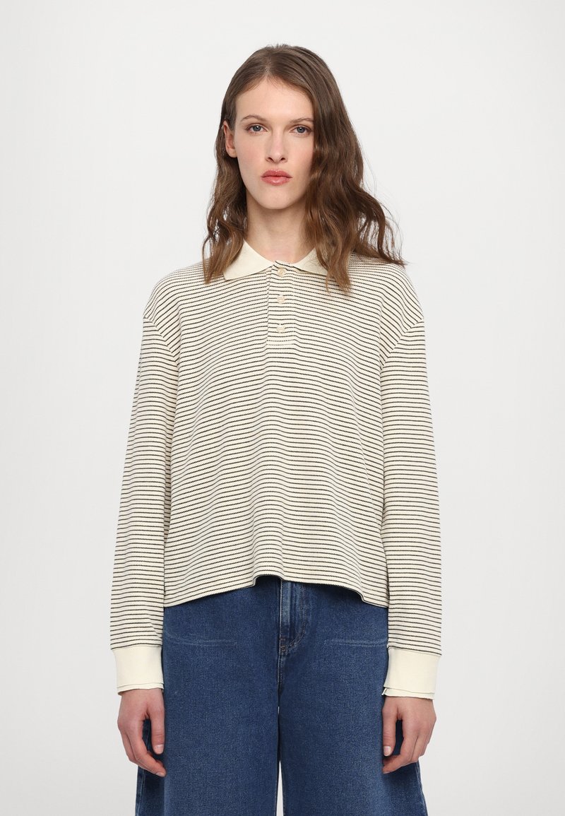 Polo a maniche lunghe a righe in crema e blu navy, con colletto, patta con tre bottoni e polsini a costine. Vestibilità casual e texture morbida.