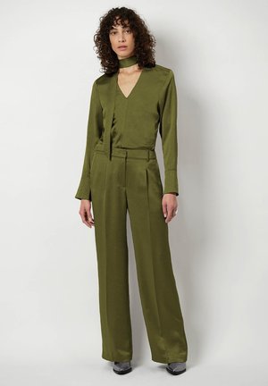 Olivengroene satijnen jumpsuit met een V-hals, lange mouwen en een strikdetail bij de hals, met wijde pijpen met plooien en een gladde textuur.
