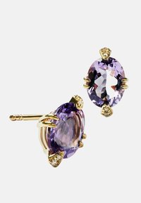Pendientes de oro que presentan piedras ovaladas de color púrpura, acentuadas con pequeñas piedras preciosas transparentes. El diseño incluye engastes en forma de garra con detalles intrincados.