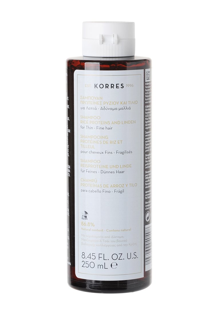 Transparante cilindrische fles shampoo, amberkleurig, met een witte dop, meertalige label en tekst die rijstproteïnen en linde benadrukt.