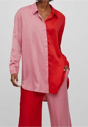 Camicia a maniche lunghe con design color block, con un lato rosa e l'altro lato rosso. Realizzata in tessuto leggero e liscio con colletto con bottoni.
