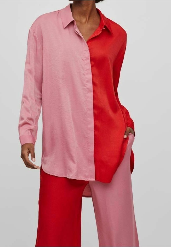 Camicia a maniche lunghe con design color block, con un lato rosa e l'altro lato rosso. Realizzata in tessuto leggero e liscio con colletto con bottoni.