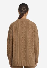 Strickpullover in Hellbraun mit strukturierten Zopfmustern, geripptem Saum und entspannter Passform. Mit Rundhalsausschnitt und langen Ärmeln.