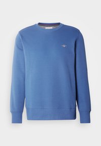 Sweat-shirt bleu à manches longues avec col rond, poignets et ourlet côtelés, petit logo brodé sur la poitrine gauche, design avant simple.