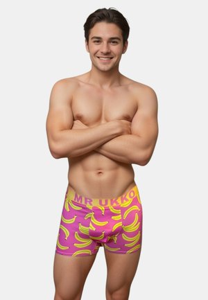 Boxers en rose avec un motif de bananes et une ceinture jaune avec le texte "MR UKKO". Fabriqué en tissu extensible pour le confort.