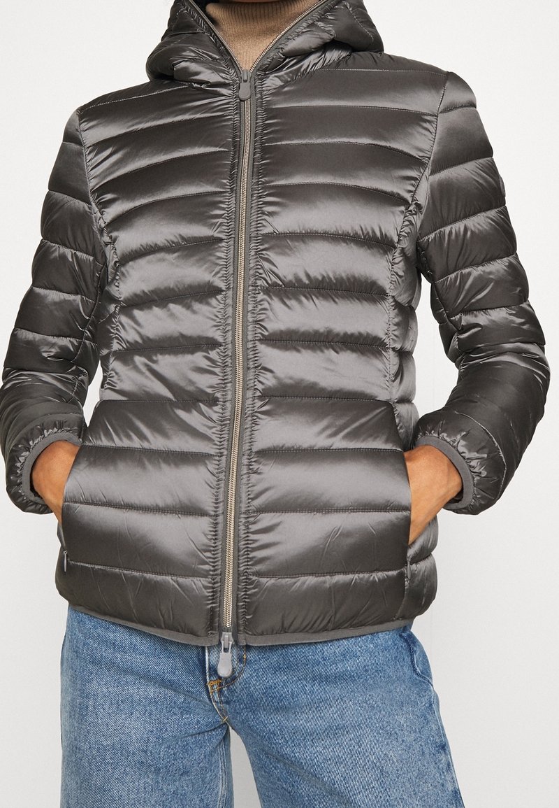 Graue Pufferjacke mit Kapuze, mit horizontalen Nähten und Seitentaschen. Hergestellt aus glänzendem, glattem Material mit einem Reißverschluss vorne.