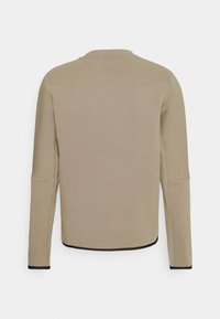 Beige Langarm-Sweatshirt mit schwarzem Saum an den Bündchen und dem unteren Saum, von hinten auf weißem Hintergrund gezeigt.