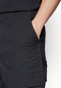 Svarta Nike cargo shorts med en strukturerad yta, med sidofickor och en liten svart logotyp på det nedre benet.