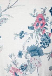 Tissu à motif floral en blanc doux, orné de fleurs roses et bleues avec des feuilles vertes, texture lisse et contours délicats.