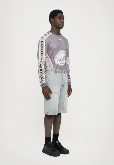 Lange mouwen grijs graphic t-shirt met een geruit patroon, gecombineerd met lichtblauwe denimshorts en zwarte sneakers. Eenvoudig casual ontwerp.