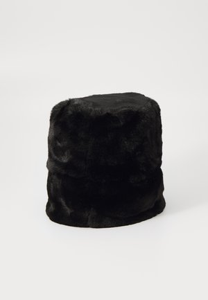 Must kahvatu kunstkarusnahast, pehme ja plüüsjas tekstuur; tsilindriline kuju, millel on kergelt kitsenev ülaosa; õmblusteta disain ja nähtamatud detailid.