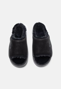 Chanclas negras con forro de piel sintética, material exterior suave, diseño de punta abierta y acento del logo de Nike en el lateral.