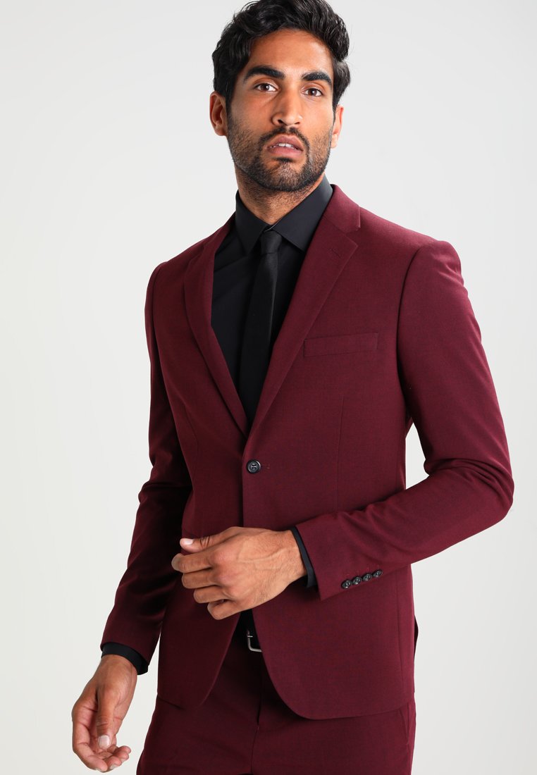 Bordó szabott öltöny egysoros gombbal, fekete inggel és slim fit fazonnal. Simasága a formális szabás mellett, bal oldali zsebével kiemeli eleganciáját.