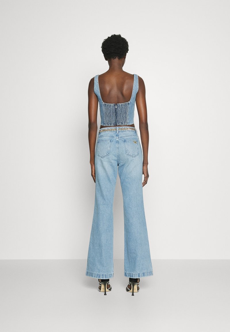 Jeansowa bluzka z marszczonym tyłem, w połączeniu z jasnoniebieskimi spodniami o szerokich nogawkach z wysokim stanem. Posiada frędzle na dole oraz ozdobne detale.