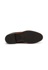Suola di scarpa in camoscio marrone con gomma nera testurizzata, che presenta una leggera curvatura nella punta e un tacco piatto, migliorando la presa e la stabilità.