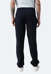 Navyblaue Jogginghose mit elastischem Bund, seitlichen Taschen, schmal zulaufendem Bein und einer einzelnen Gesäßtasche, aus weichem Baumwollmischmaterial.