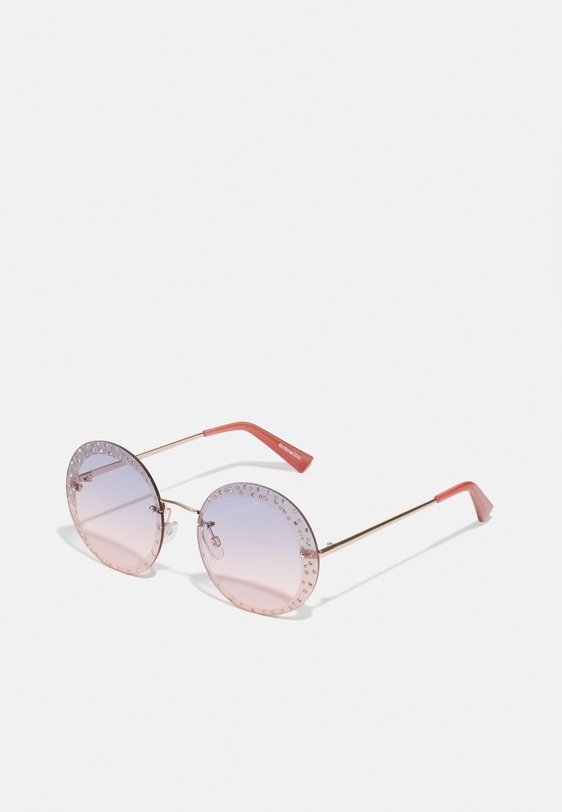Occhiali da sole tondi con montatura in metallo dorato, lenti rosa chiaro e un design borchiato lungo i bordi. Accenti arancioni sulle astine.