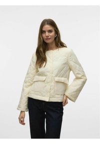 Chaqueta acolchada en crema con cuello redondo, botones delanteros y dos grandes bolsillos. Presenta mangas anchas y una silueta estructurada.