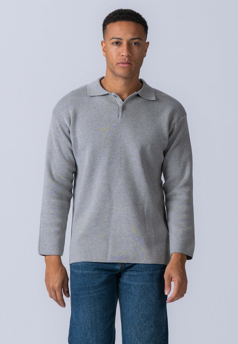Grå langærmet polo shirt med krave og kort lynlås. Blød tekstur og lige snit, parret med blå jeans.