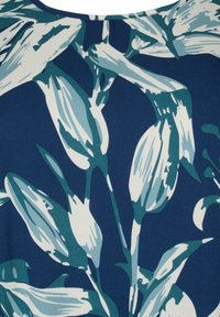 Marinblått tyg med en botanisk tryck bestående av vita och teal blommönster. Texturerad yta med varierande nyanser av grönt och blått.