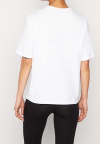 Vit bomullströja med korta ärmar, rundad halsringning och rak passform. Bakstycket är helt utan synliga grafik eller dekorationer.