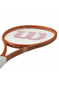 Racchetta da tennis con un telaio arancione, un motivo di corde bianco e un logo sulla gola. Presenta una presa liscia e un design della testa arrotondato.