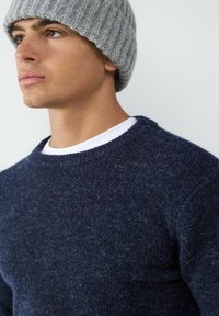 Chabrowy sweter w robione na drutach z teksturowym wykończeniem, okrągłym dekoltem i prążkowymi detalami, w zestawieniu z jasnoszarym, prążkowanym czapką.