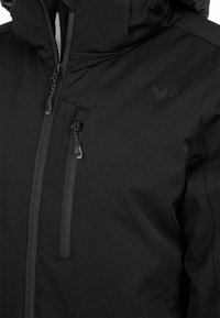 Schwarze wasserdichte Jacke mit hohem Kragen, Reißverschlussdetails, mehreren Taschen und einem kleinen geprägten Logo auf der oberen linken Seite.