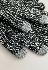 Pletene rokavice v črni in beli barvi z sivimi pletenimi konicami. Imajo teksturiran vzorec in mehko, debelo material za toploto.