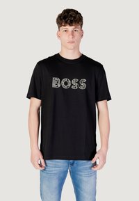 Zwarte katoenen t-shirt met het woord "BOSS" in contrasterende, gestructureerde typografie, ronde halslijn en korte mouwen.