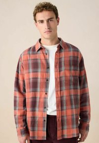 Geruite flanellen shirt in oranje, bordeaux en blauwe tinten; knoopsluiting; lange mouwen; enkele borstzak; zachte textuur.