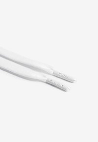 Lacci bianchi con tessuto testurizzato, dotati di estremità piatte in rilievo con le parole "protect" e "crep."